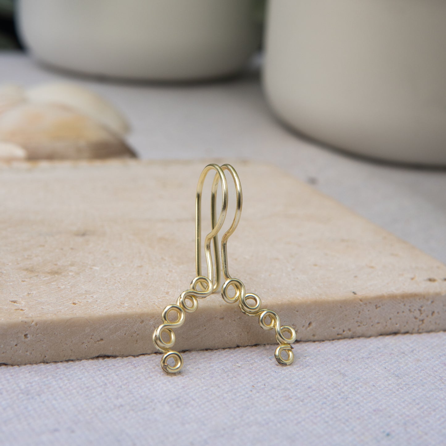 This is a gold-toned faux lip ring made with light gold copper wire. The wire design spirals into two diagonal directions, forming five tightly moulded circles.
