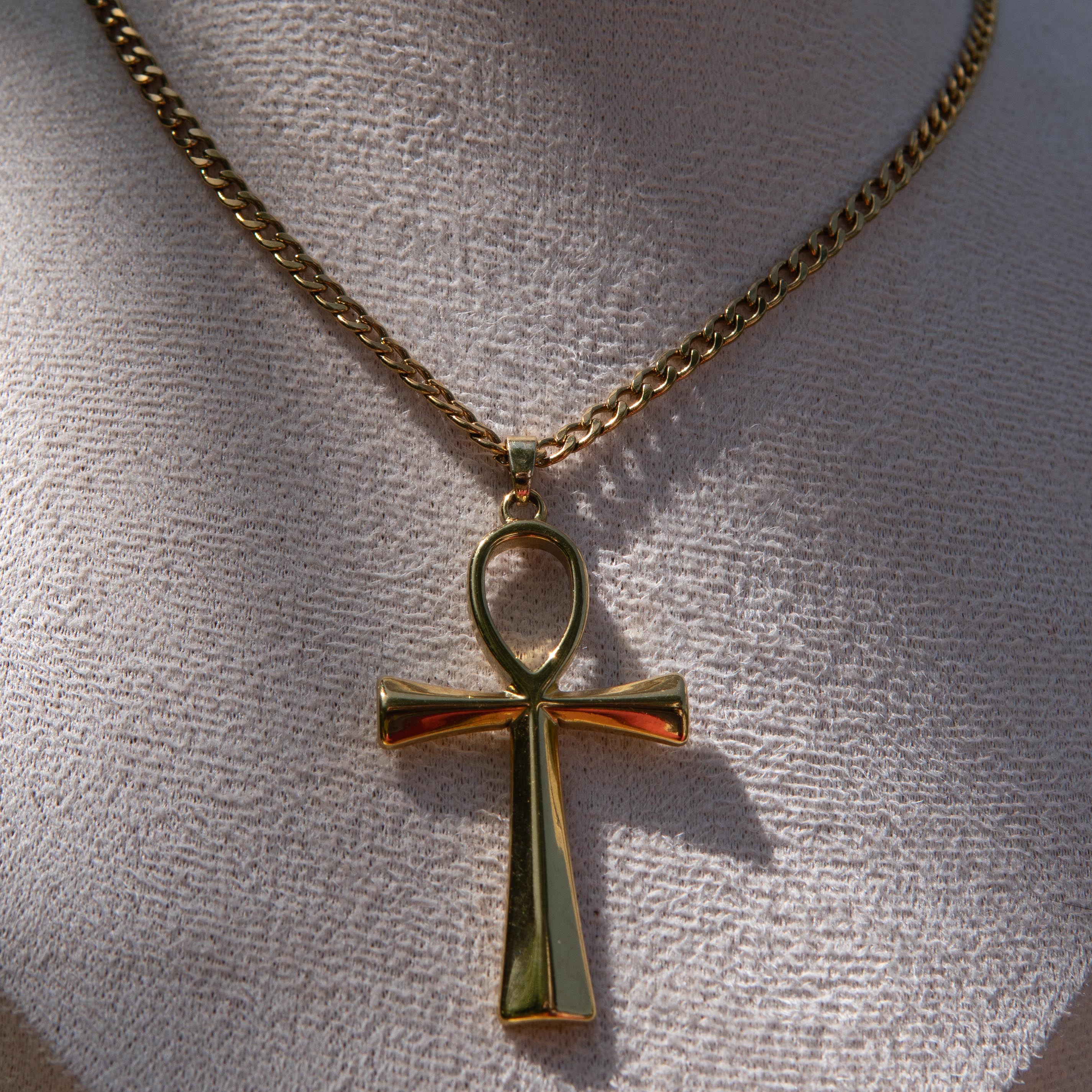 Gold necklace with an ankh pendant displayed on a mannequin bust.