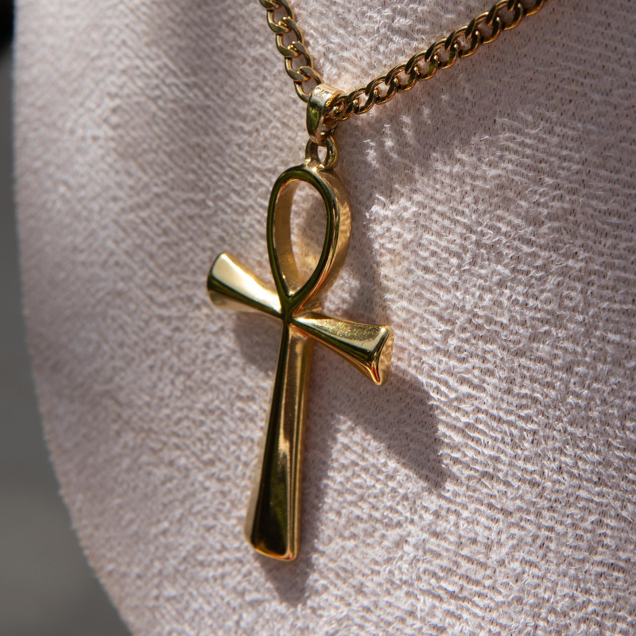Gold necklace with an ankh pendant displayed on a mannequin bust.