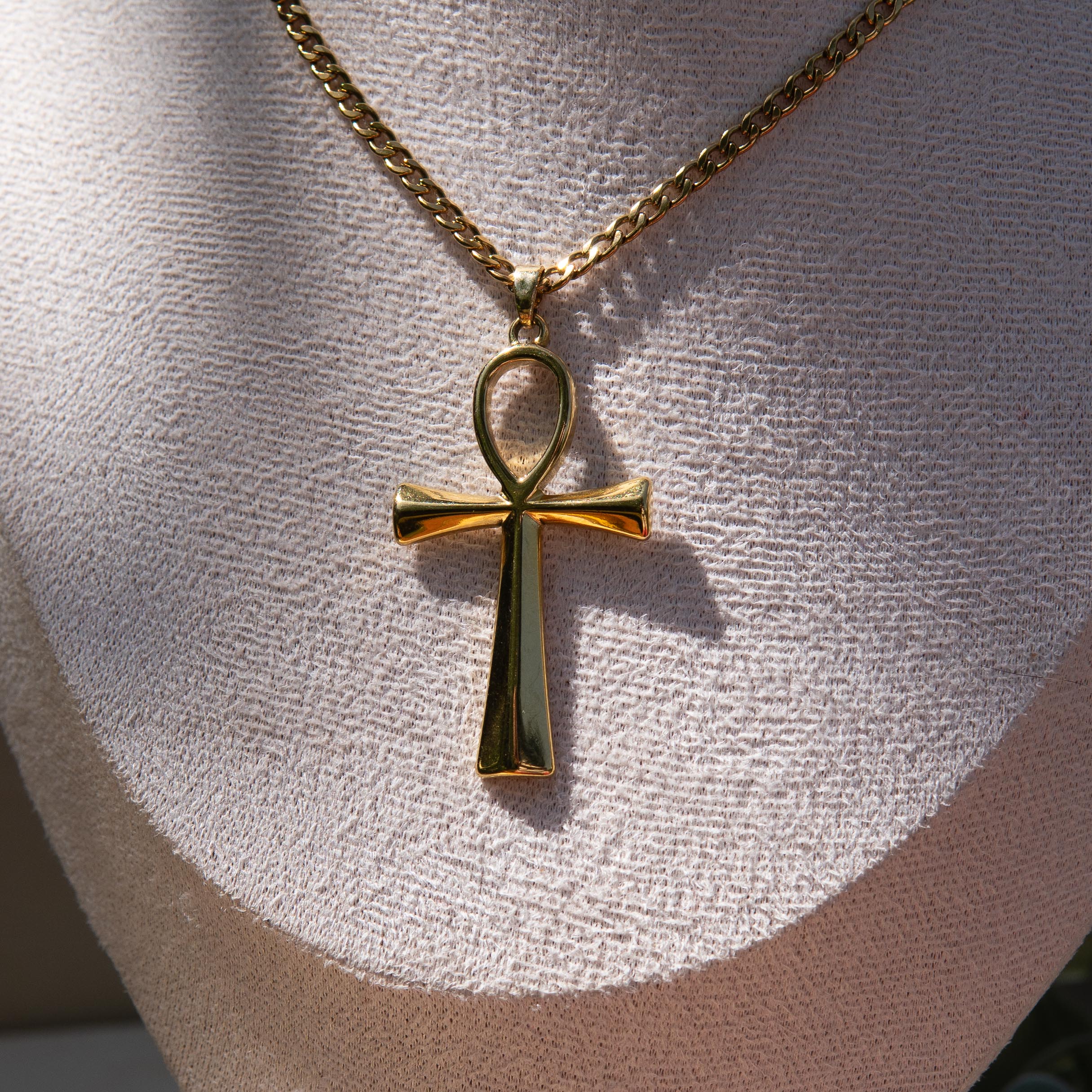 Gold necklace with an ankh pendant displayed on a mannequin bust.