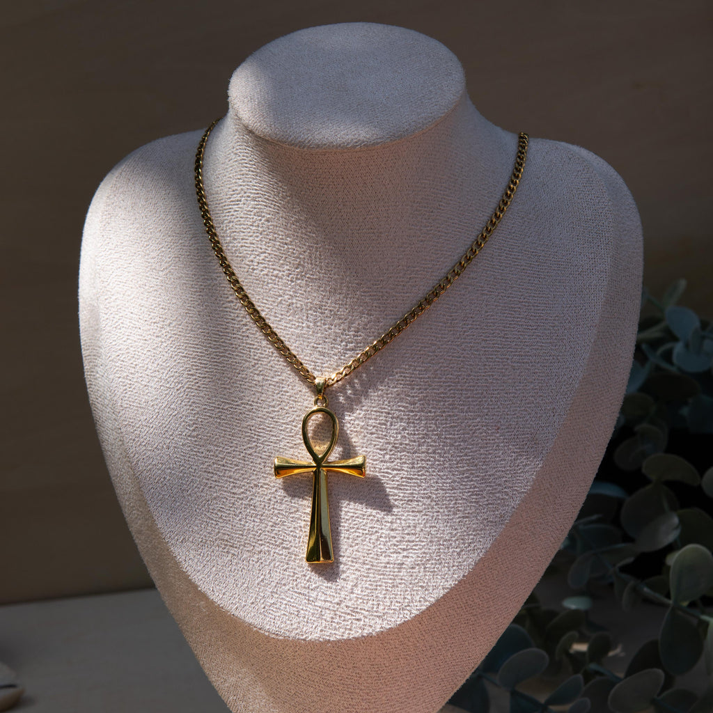 Gold necklace with an ankh pendant displayed on a mannequin bust.