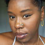 A gold-toned faux nose ring adorns the model's nose in a circular wire design that spirals up and gradually decreases in size. A crystal amazonite gemstone is woven into the design and rests at the bottom.