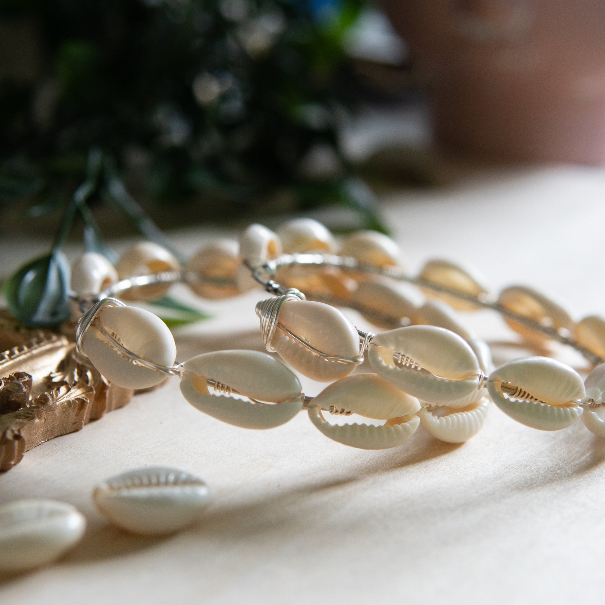 Large silver hoop earrings with cream-toned natural cowrie shells tightly wire-wrapped around the design's circumference.