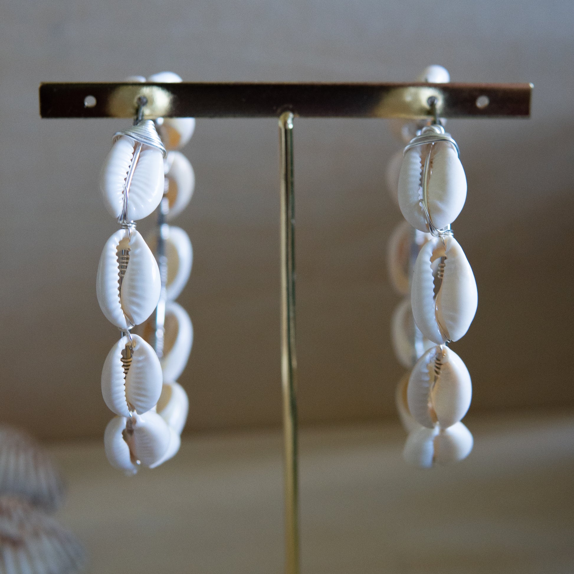 Large silver hoop earrings with cream-toned natural cowrie shells tightly wire-wrapped around the design's circumference.