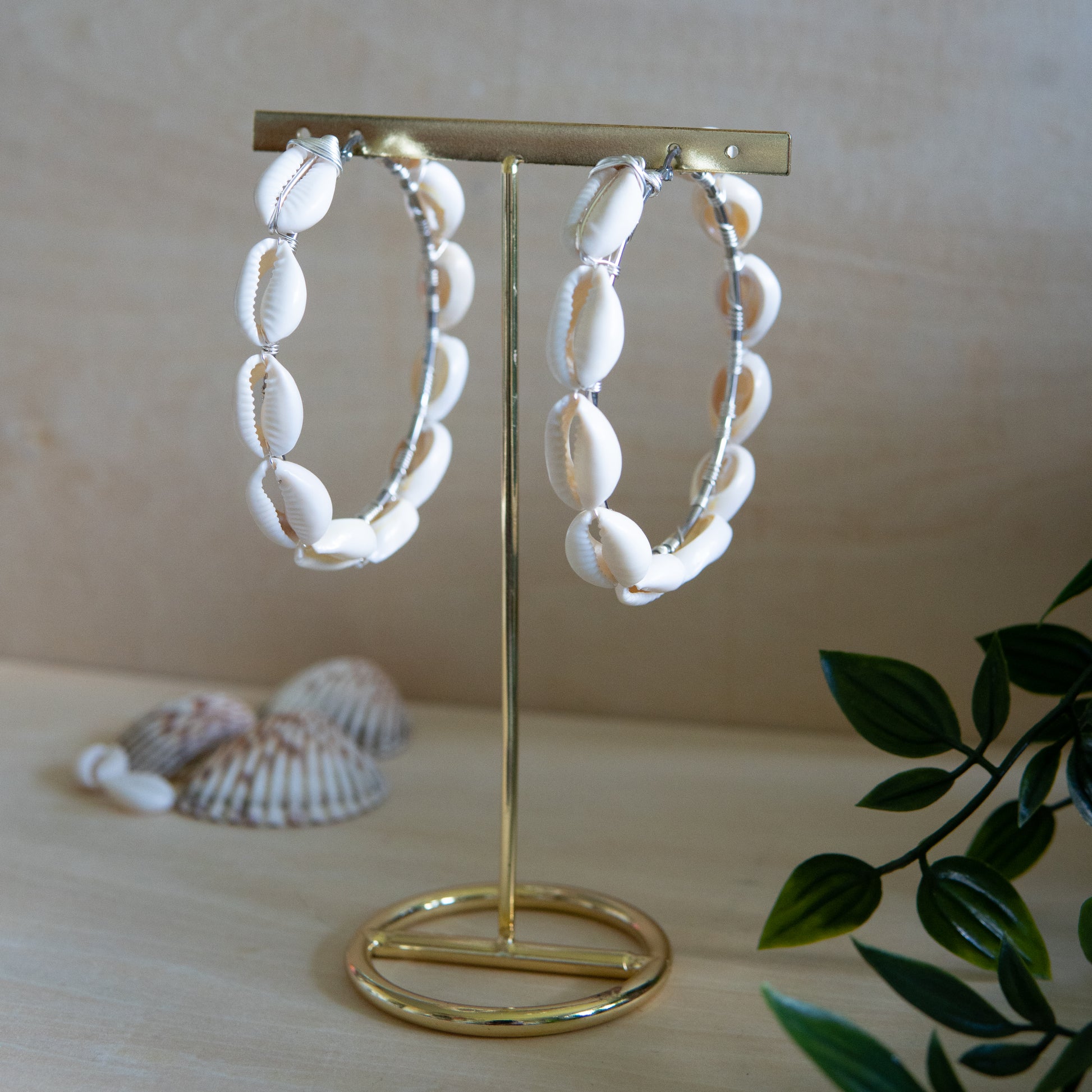 Large silver hoop earrings with cream-toned natural cowrie shells tightly wire-wrapped around the design's circumference.