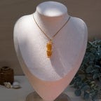 Gold wire-wrapped yellow agate pendant necklace shown on a white fabric bust.