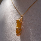 Gold wire-wrapped yellow agate pendant necklace displayed on a white fabric bust