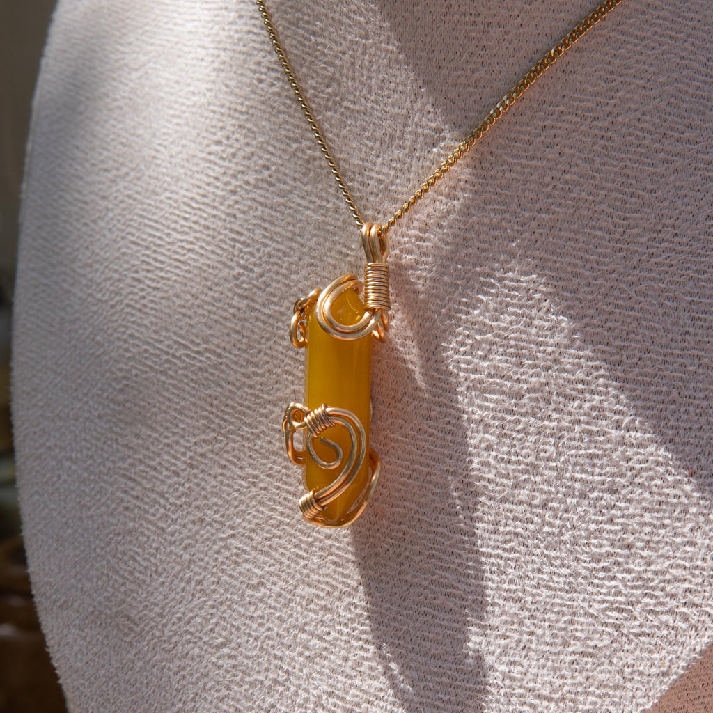 Gold wire-wrapped yellow agate pendant necklace displayed on a white fabric bust