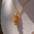 Gold wire-wrapped yellow agate pendant necklace displayed on a white fabric bust