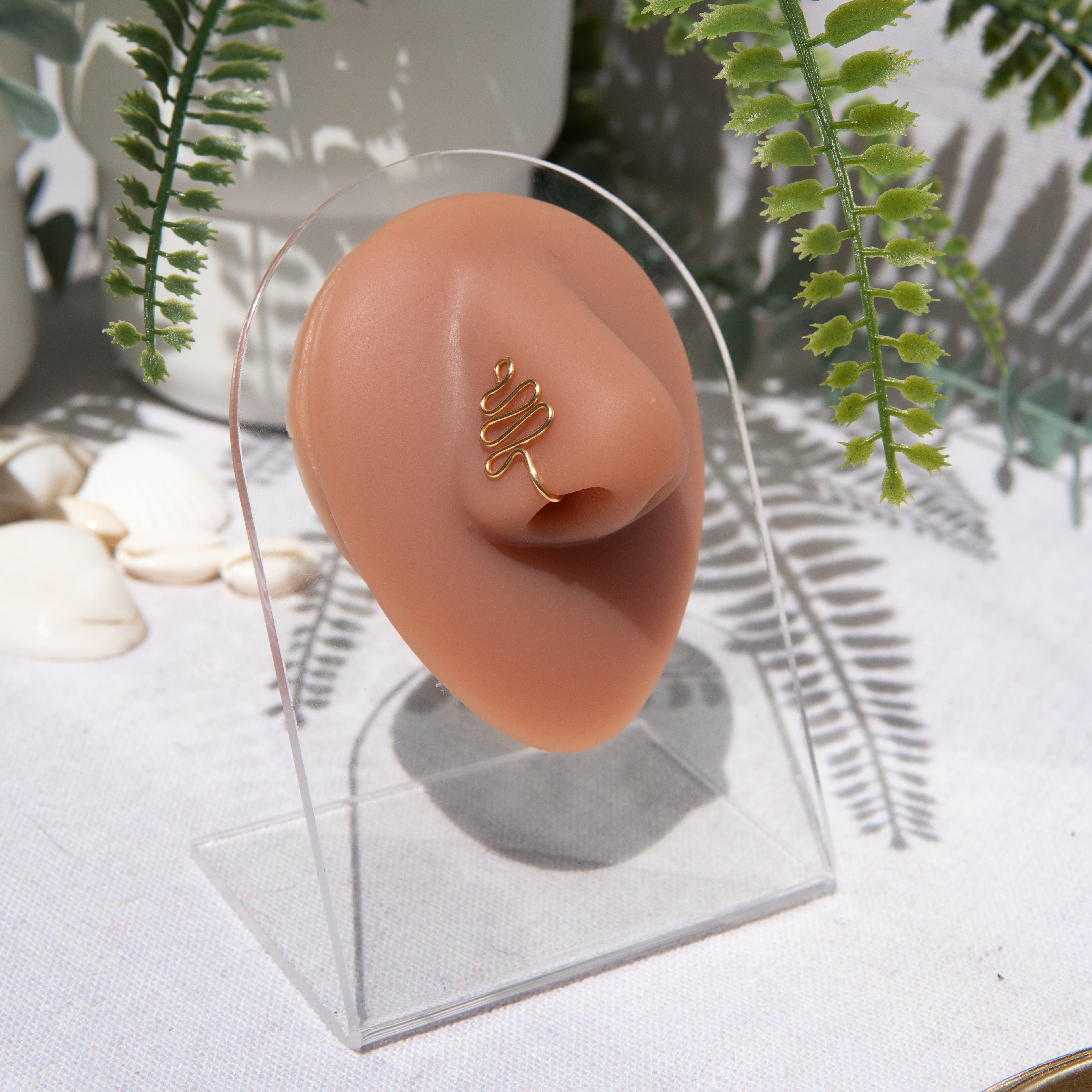 A gold-toned faux nose ring cuffs the model's nose. The wire design moulds a wavy pyramid shape.A gold-toned faux nose ring cuffs the model's nose. The wire design moulds a wavy pyramid shape.