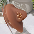 A gold-toned faux nose ring cuffs the model's nose. The wire design moulds a wavy pyramid shape.