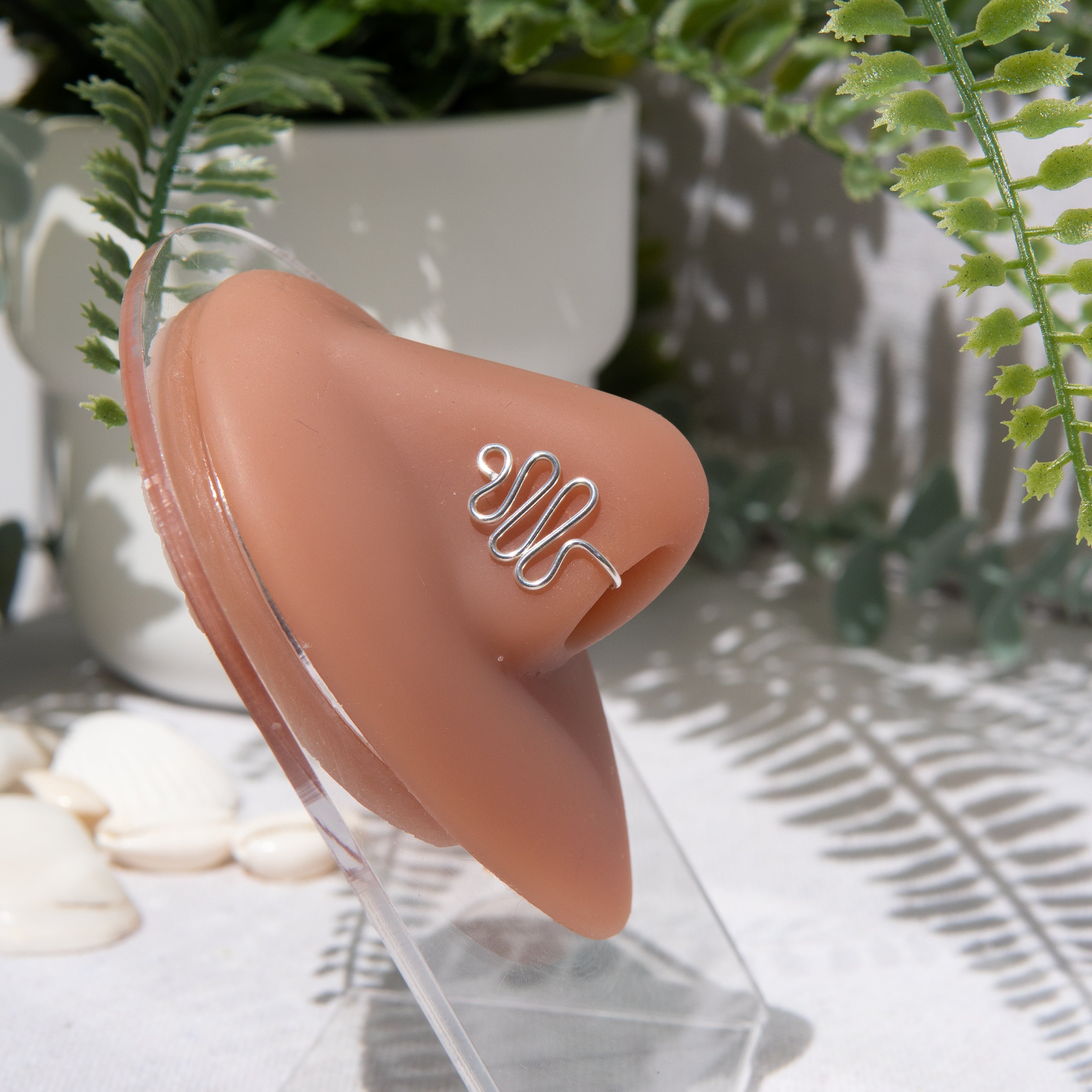 A silver-toned faux nose ring cuffs the model's nose. The wire design forms a wavy pyramid shape.
