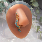 A gold-toned faux dangle nose ring cuffs the model's nostrils. Blue seed beads are wire-wrapped around the hoop's circumference, with three beaded gold chains dangling down.