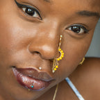 A gold-toned faux dangle nose ring cuffs the model's nostrils. Yellow transparent seed beads are wire-wrapped around the hoop's circumference, with three beaded gold curb chains dangling down.