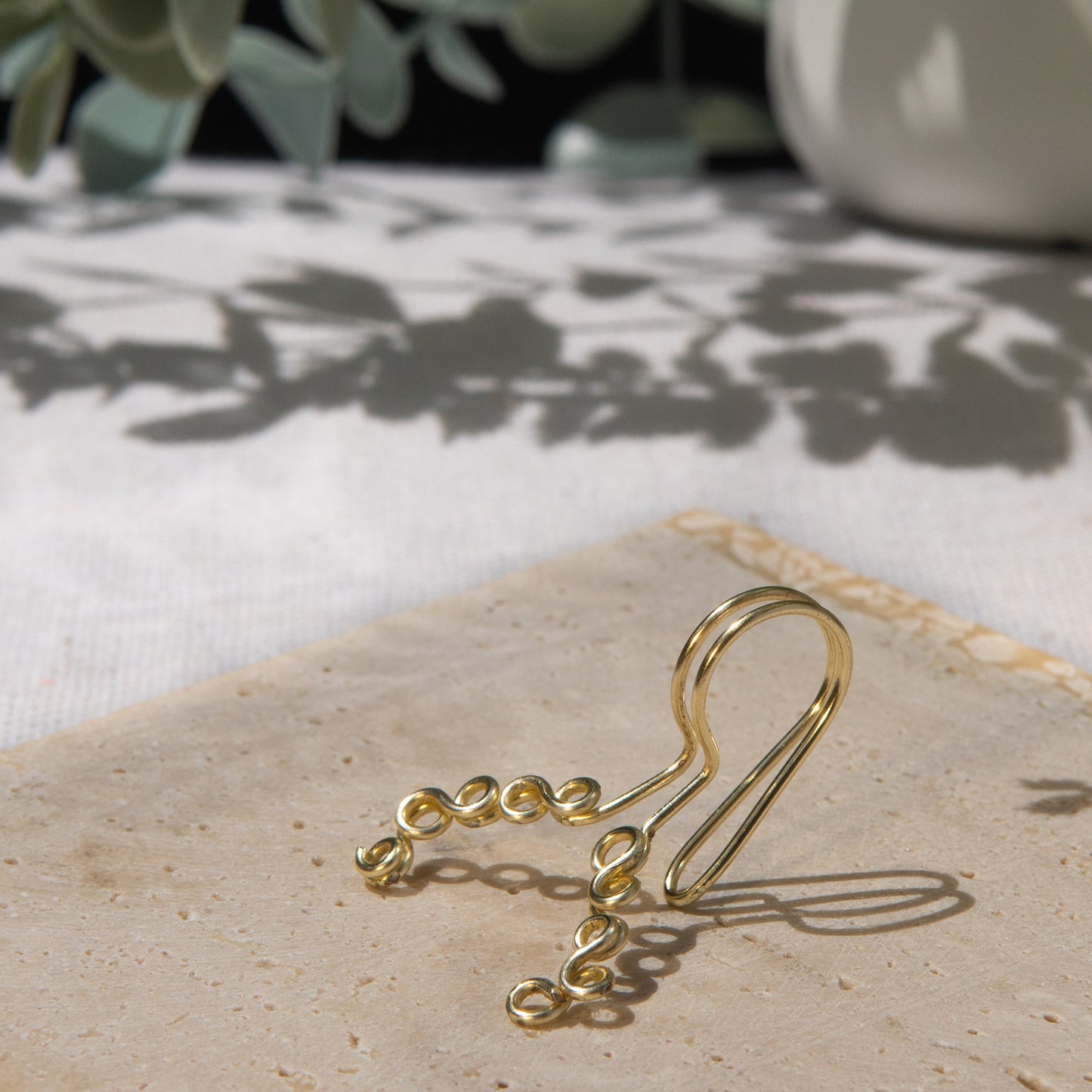 This is a gold-toned faux lip ring made with light gold copper wire. The wire design spirals into two diagonal directions, forming five tightly moulded circles.