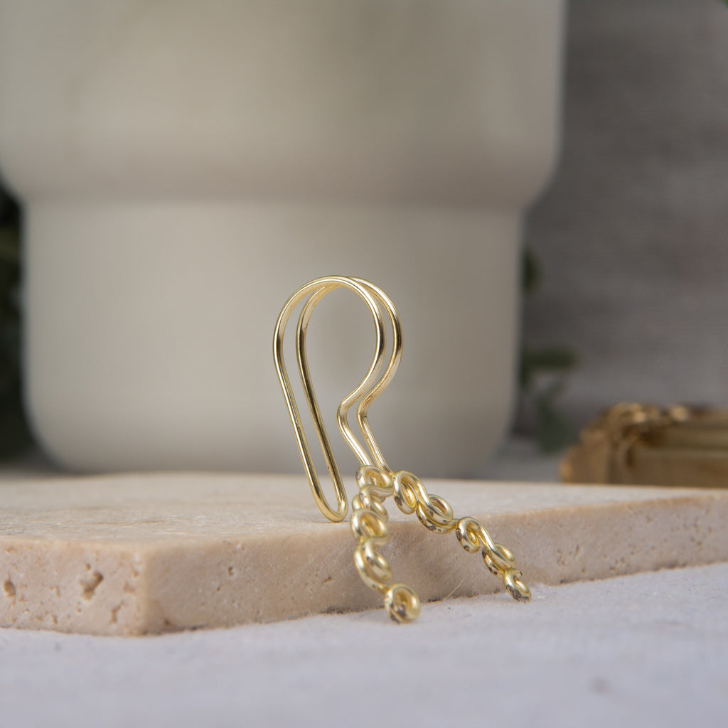 This is a gold-toned faux lip ring made with light gold copper wire. The wire design spirals into two diagonal directions, forming five tightly moulded circles.