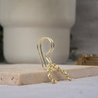 This is a gold-toned faux lip ring made with light gold copper wire. The wire design spirals into two diagonal directions, forming five tightly moulded circles.