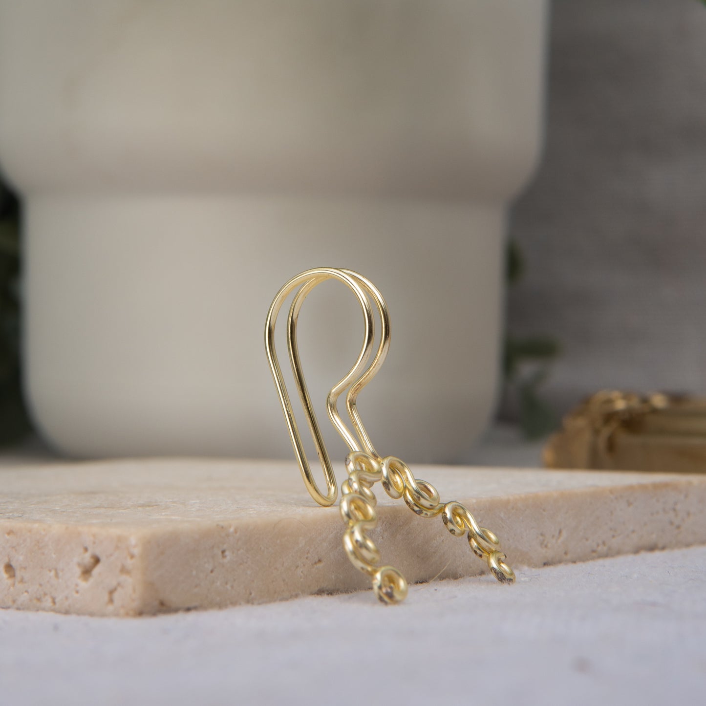 This is a gold-toned faux lip ring made with light gold copper wire. The wire design spirals into two diagonal directions, forming five tightly moulded circles.