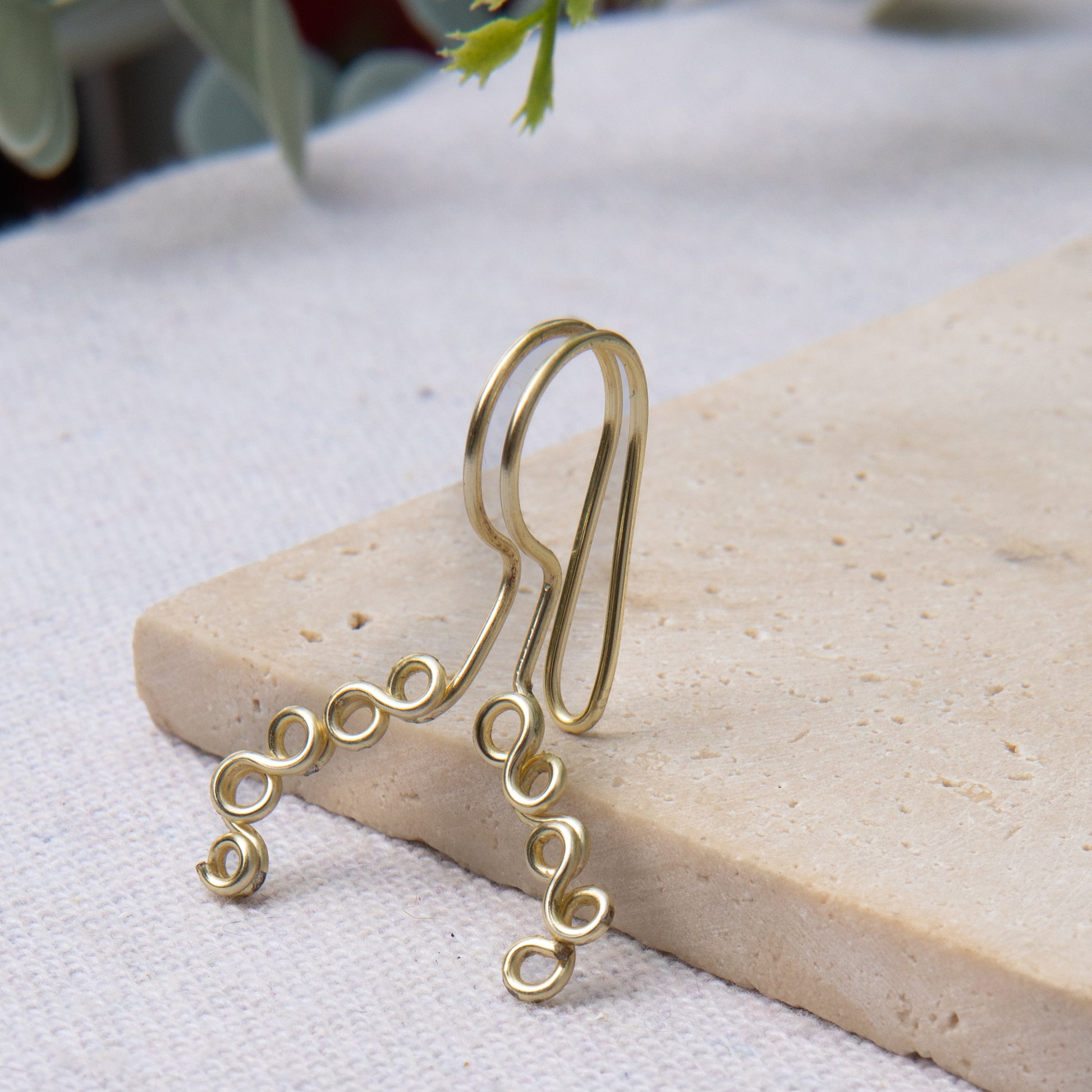 This is a gold-toned faux lip ring made with light gold copper wire. The wire design spirals into two diagonal directions, forming five tightly moulded circles.