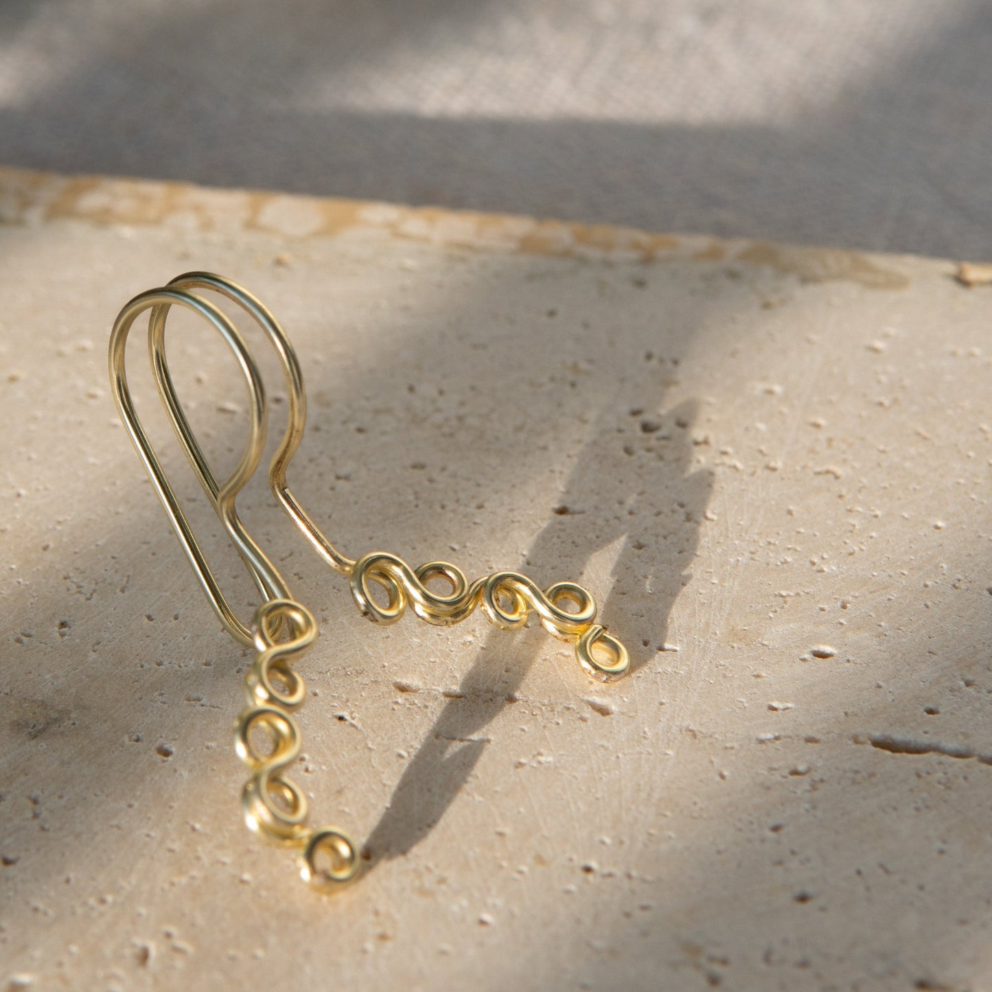 This is a gold-toned faux lip ring made with light gold copper wire. The wire design spirals into two diagonal directions, forming five tightly moulded circles.