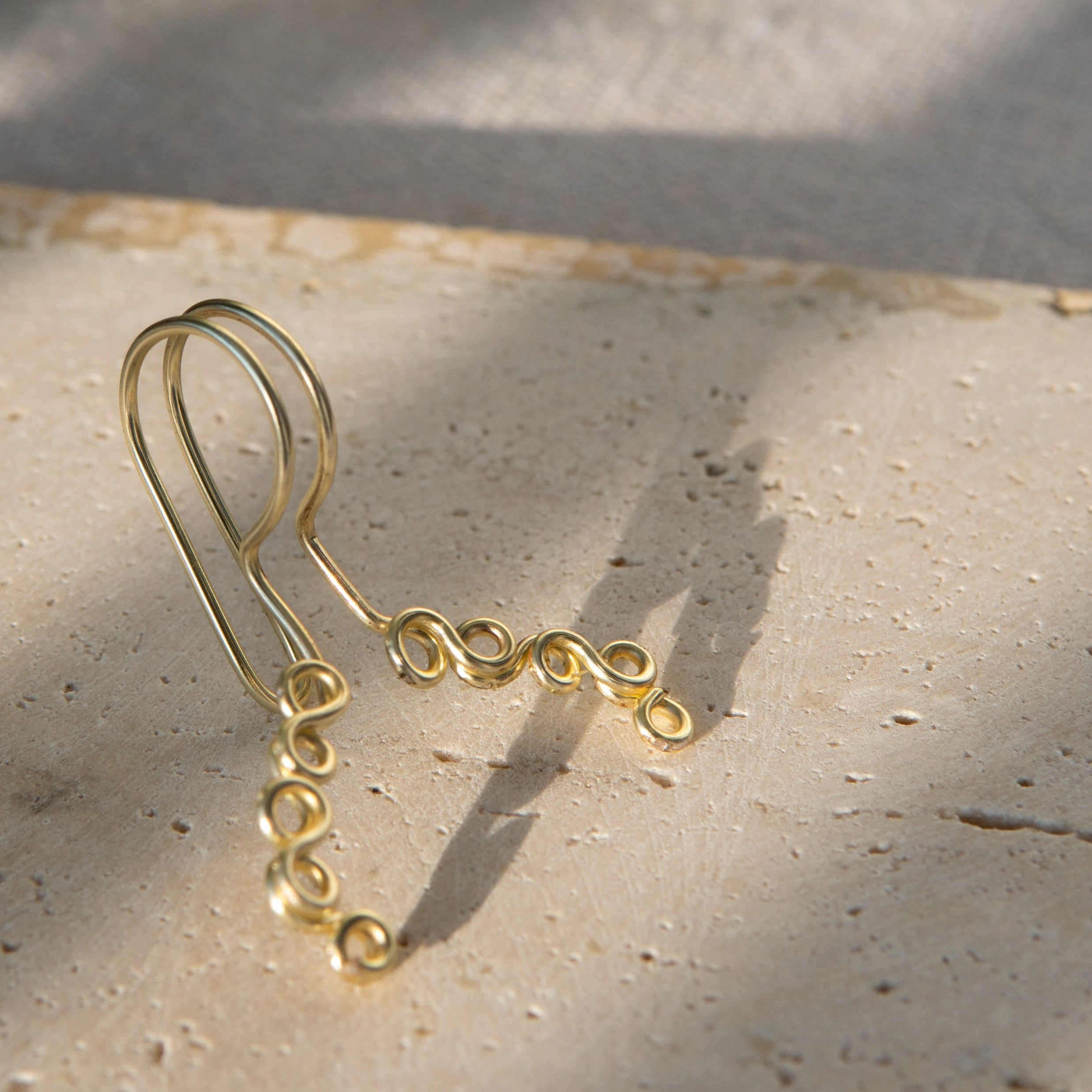 This is a gold-toned faux lip ring made with light gold copper wire. The wire design spirals into two diagonal directions, forming five tightly moulded circles.