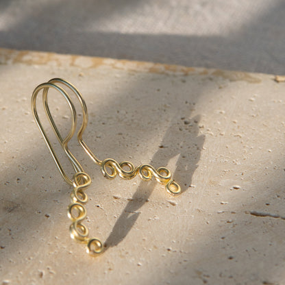 This is a gold-toned faux lip ring made with light gold copper wire. The wire design spirals into two diagonal directions, forming five tightly moulded circles.