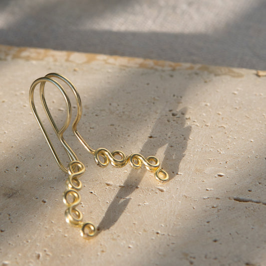 This is a gold-toned faux lip ring made with light gold copper wire. The wire design spirals into two diagonal directions, forming five tightly moulded circles.
