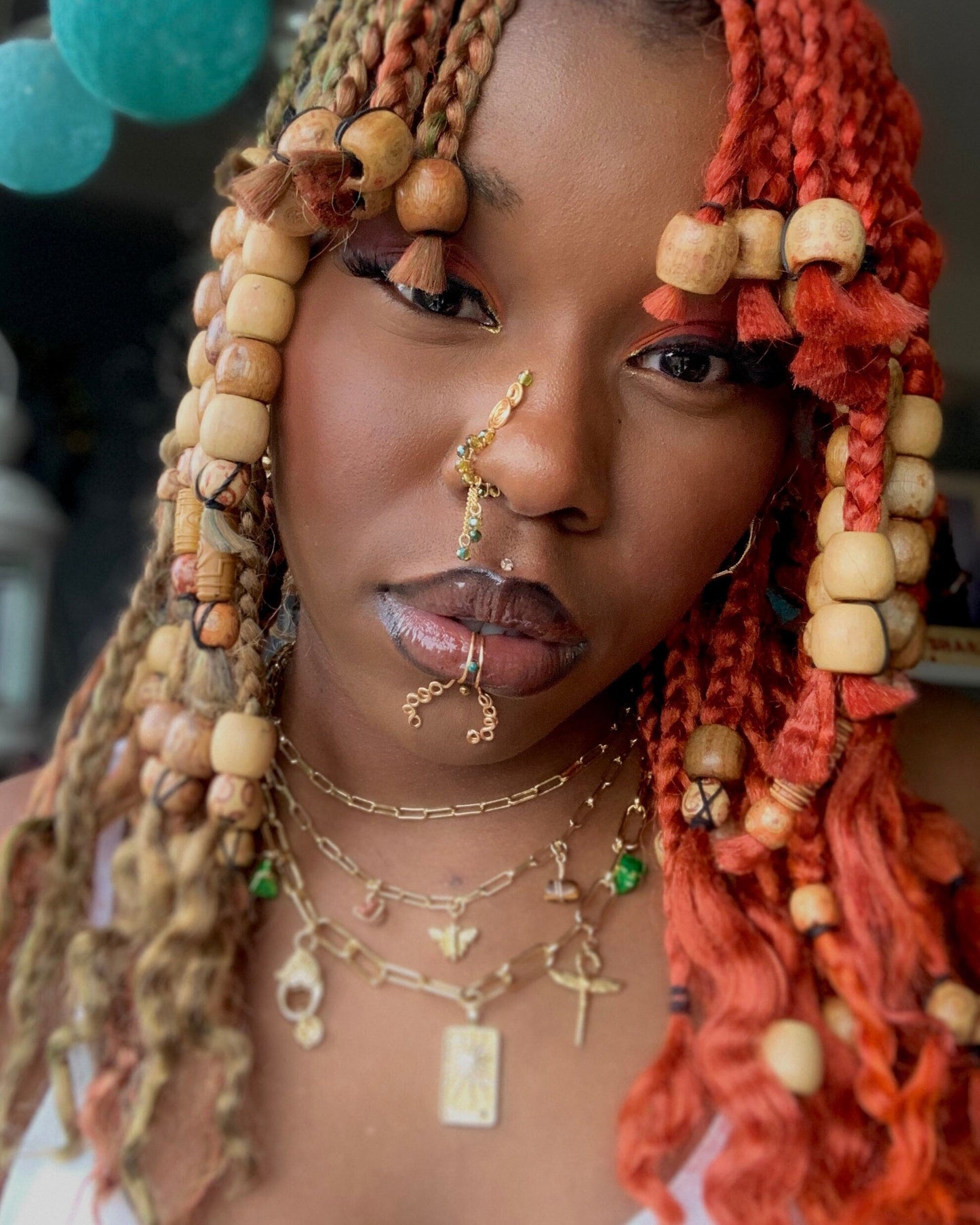 A gold-toned, tightly spiralled faux lip ring cuffs the centre of the model's bottom lip. The wire design spirals into two diagonal directions, forming five tightly moulded circles that rest against the model's chin.