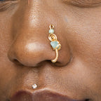 A gold-toned faux nose ring cuffs the model's nostril. A green aventurine crystal gemstone is wire-wrapped and interweaved into a vertical spiral wire design.