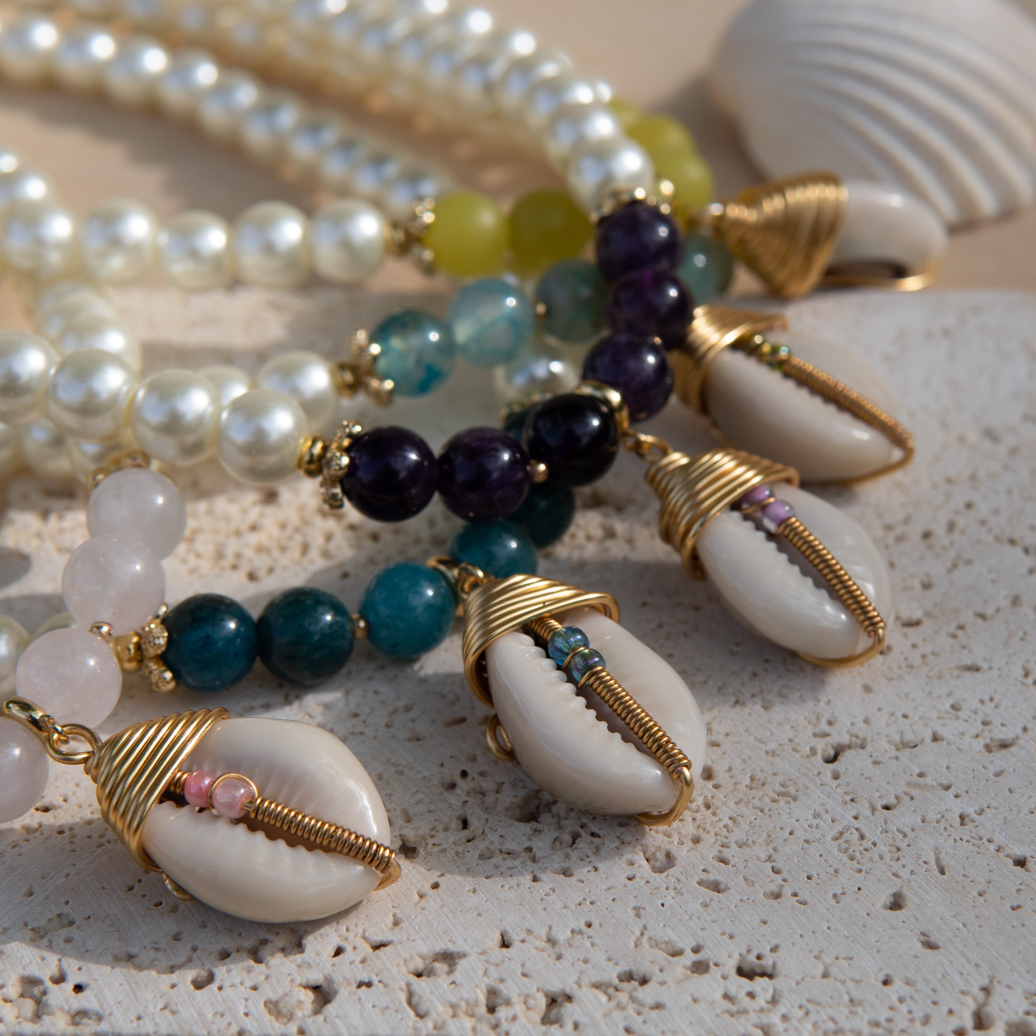Beaded bracelets with shells on a sandy surface